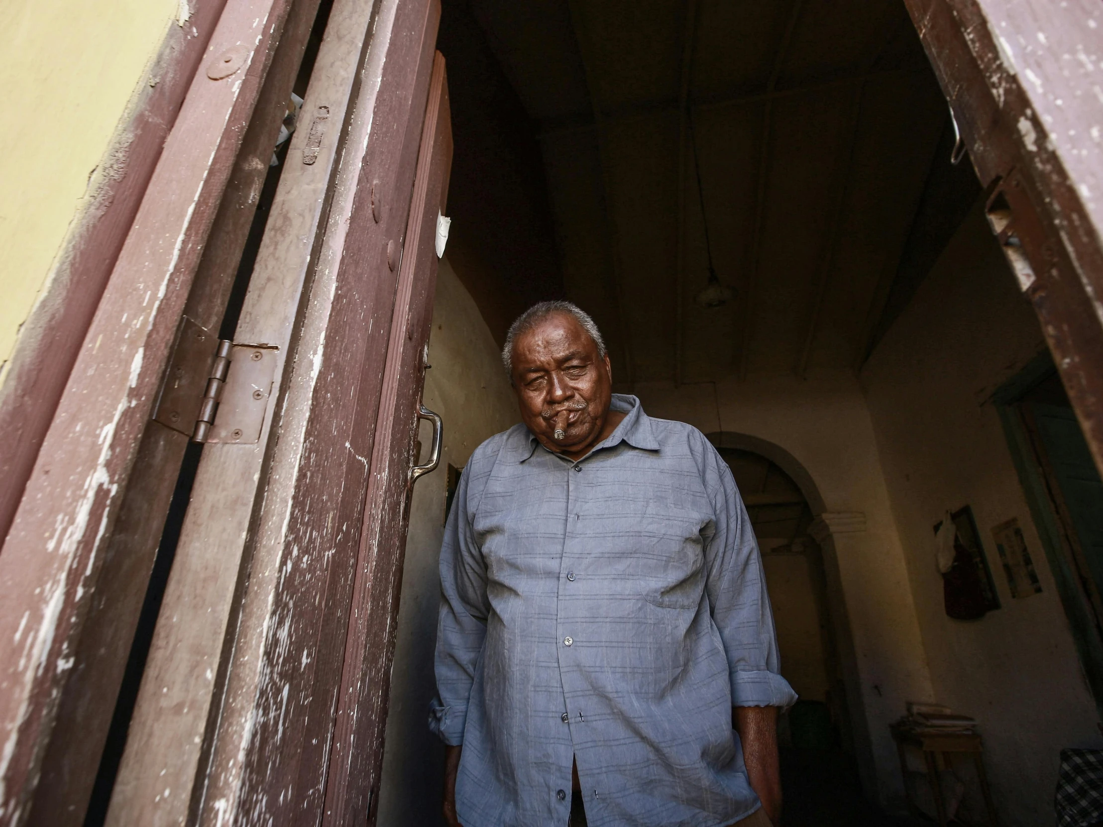 a man in a blue shirt stands near an open door