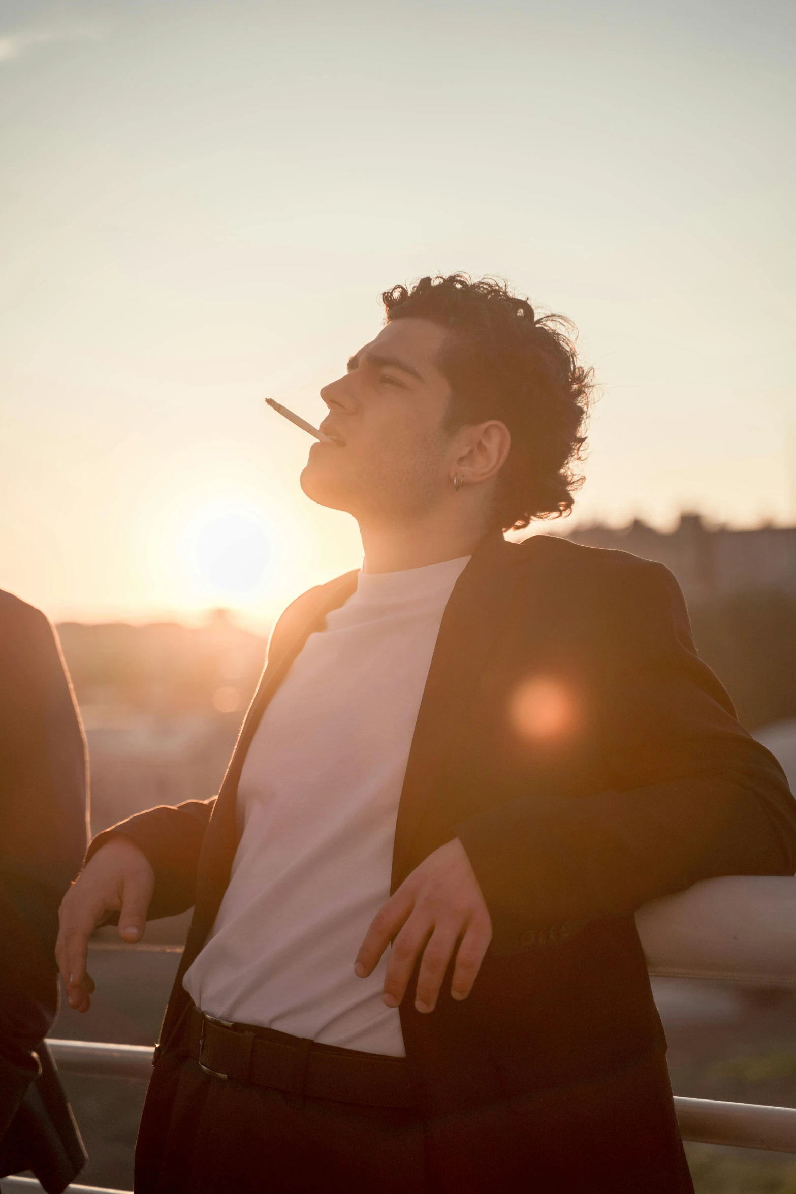 a man smoking cigarette in front of the sun