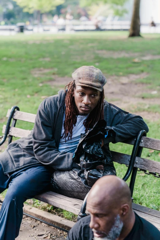 a person with dreadlocks is sitting on a bench