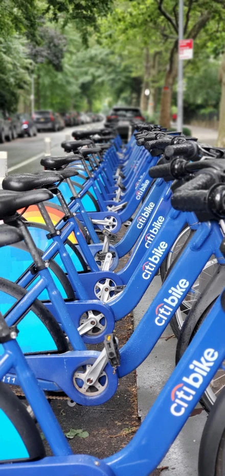 several parked bikes, in different colors, along the side of a street