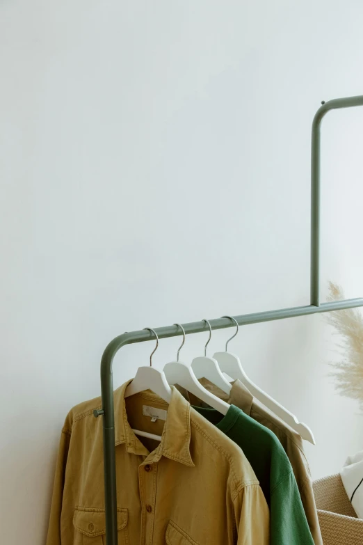 a rail holding clothes in different shades of green