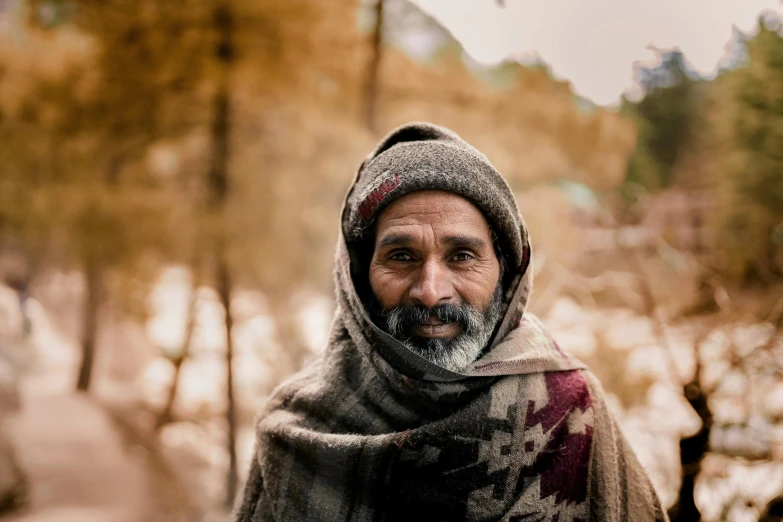 a man in winter clothing standing by a tree covered path