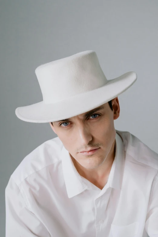 a man in a white shirt and white hat posing for the camera