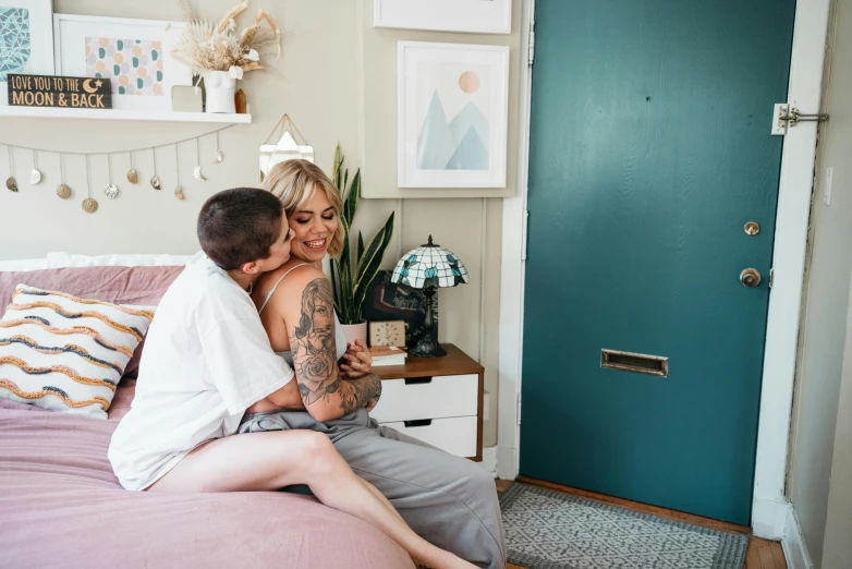 two people sitting on a bed holding each other