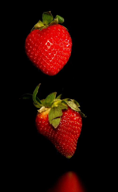 two red strawberries against a dark background