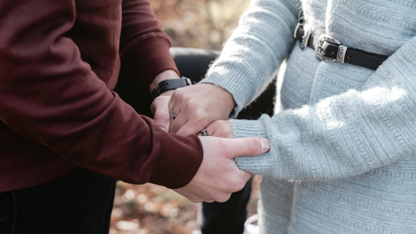 two people who are holding hands in front of the camera