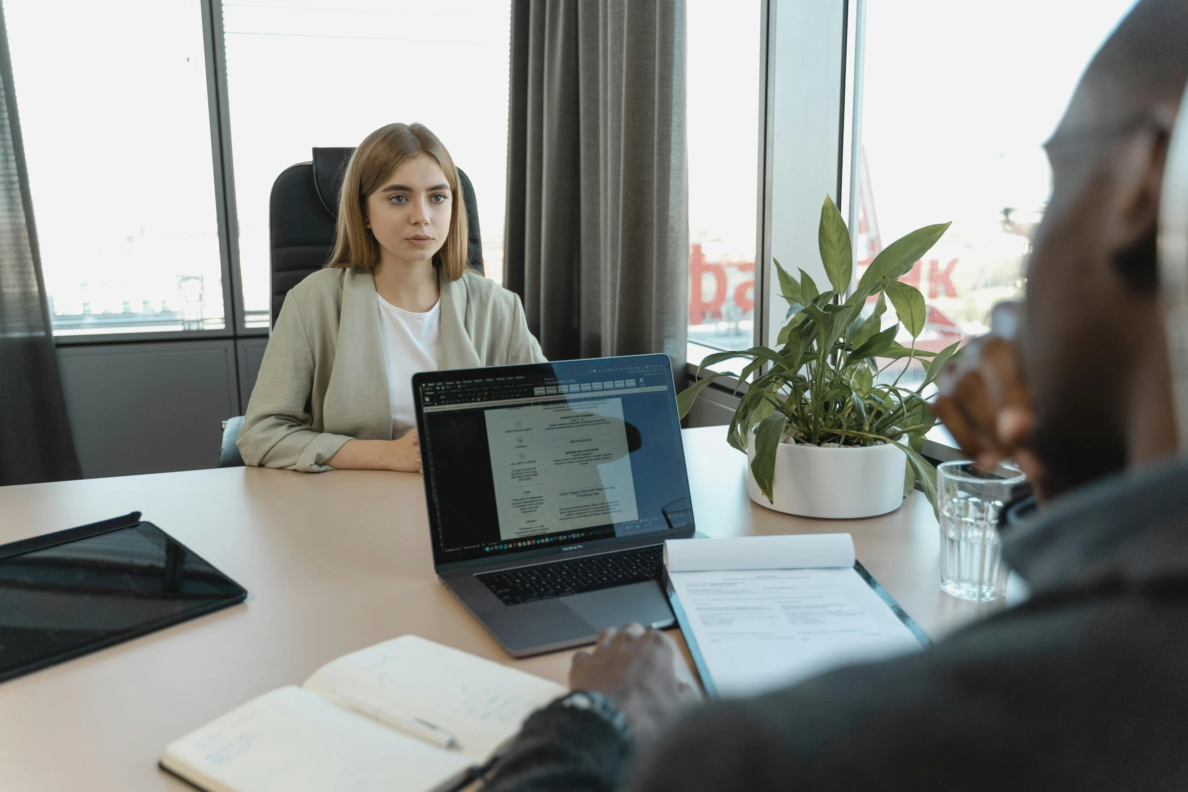 a man sitting at a desk while two women are using laptops