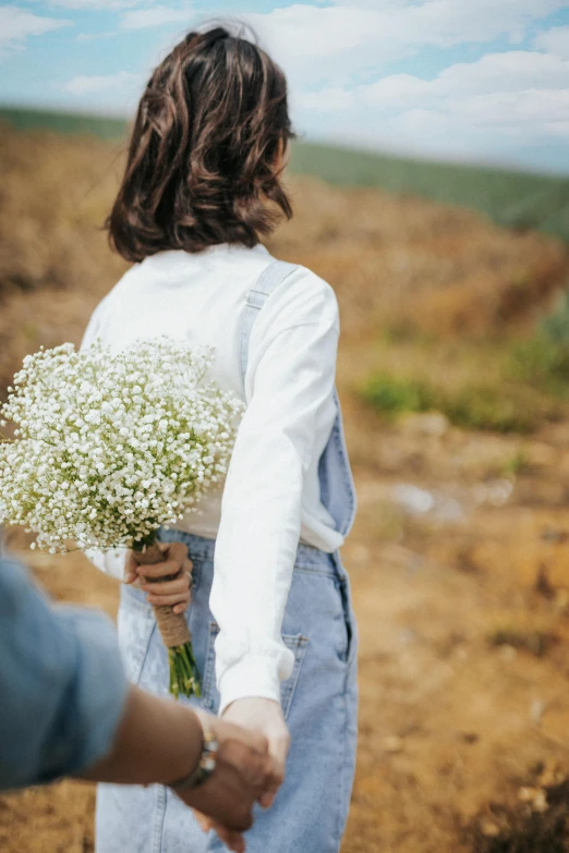 someone holding the back of their bouquet of daisies