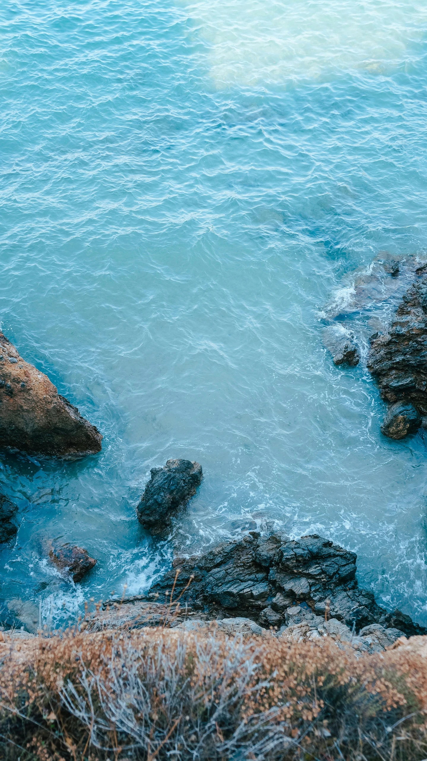 a view from above of water with rocks and grass