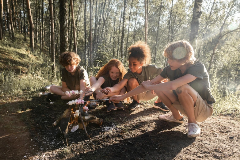 five young children sitting on a hill by a campfire