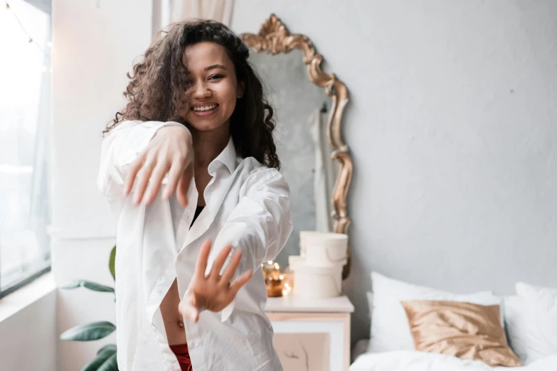 a woman in a white shirt smiles as she throws out her arms