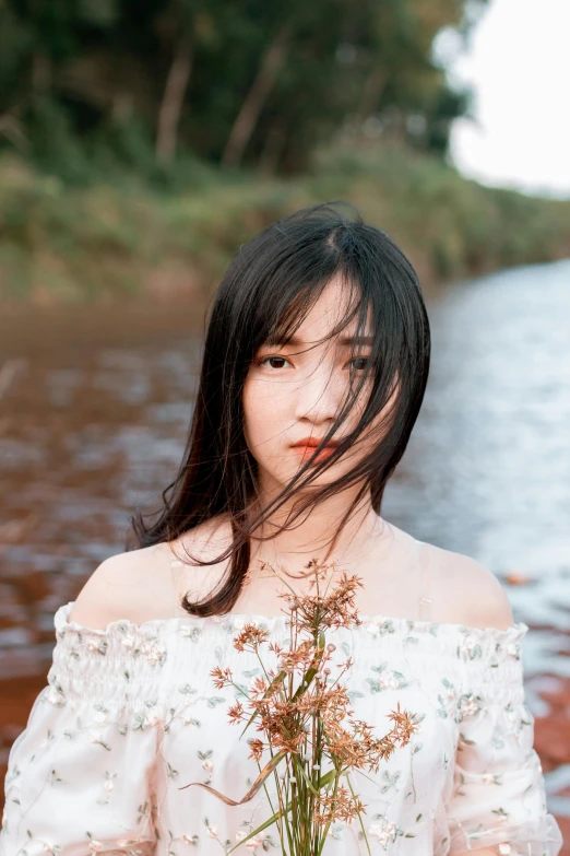 woman in off the shoulder white top next to the river