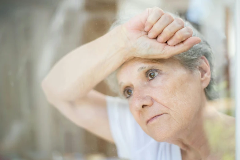 a woman with short hair holding her head by the window