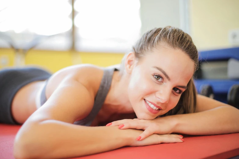 a smiling woman is laying down on the mat