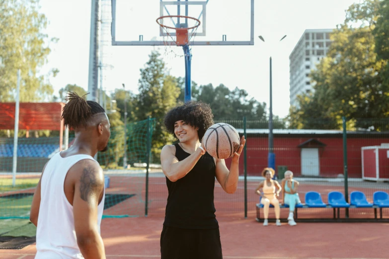 two young men on a basketball court holding basketballs