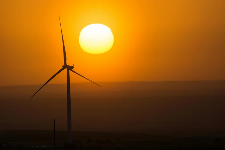 a wind turbine stands out against a sunset