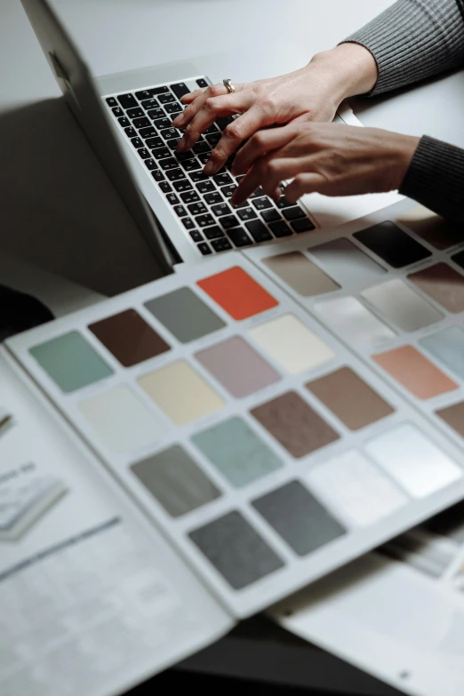 hands on top of a computer keyboard and assorted color samples