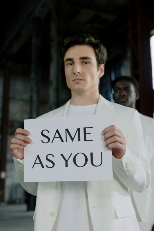 man holding a sign saying same as you