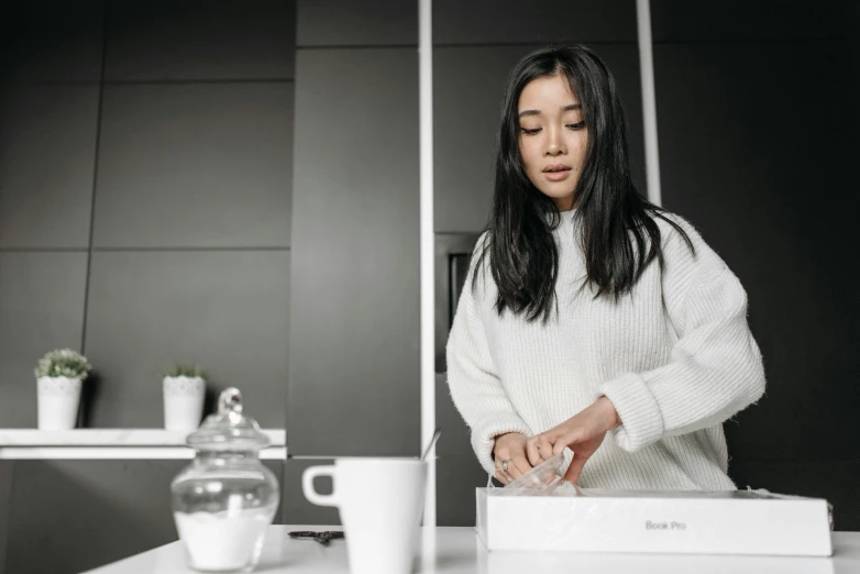 woman in white sweater preparing food at table