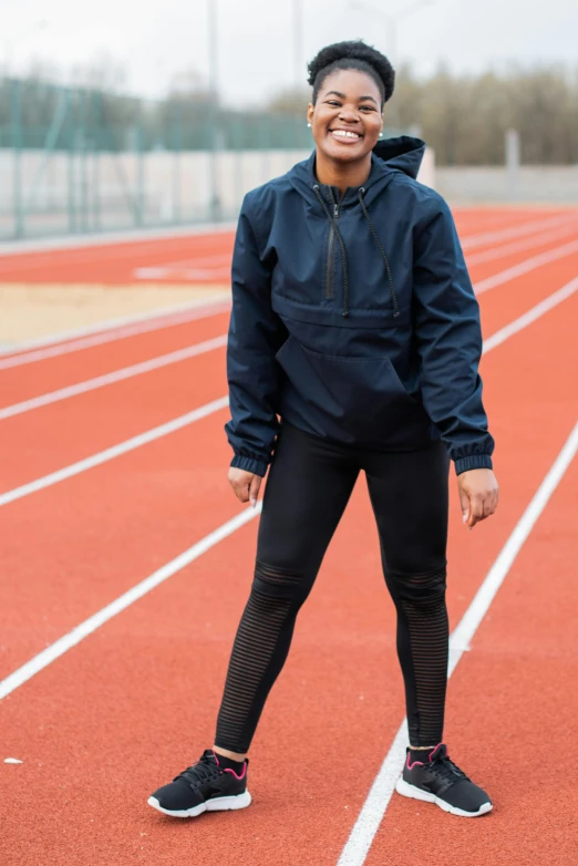 a female in tights standing on a track smiling