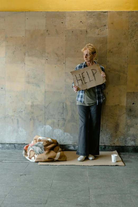 a person holding up a sign by some sand bags