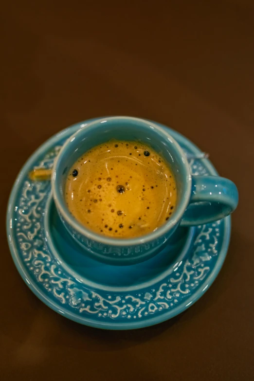 cup of  beverage on saucer sitting on brown surface