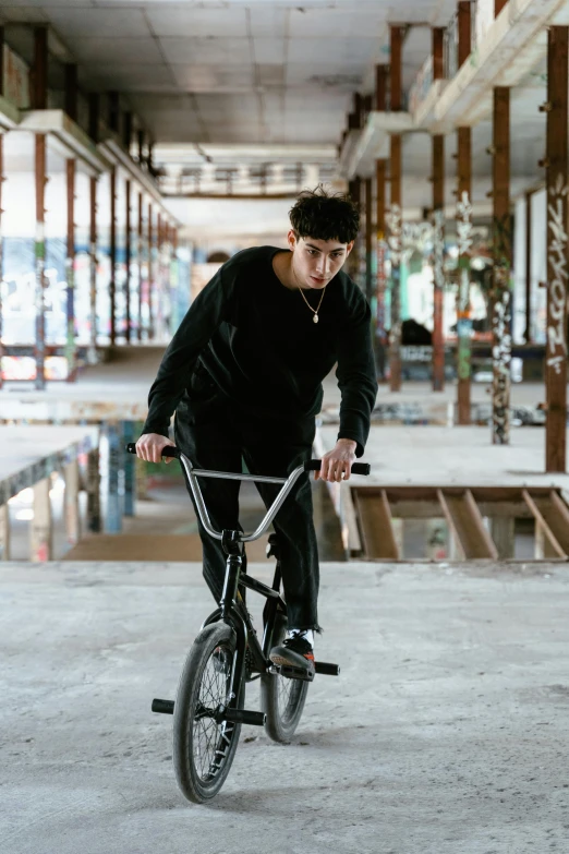 a man riding on the back of a bicycle in an empty parking lot