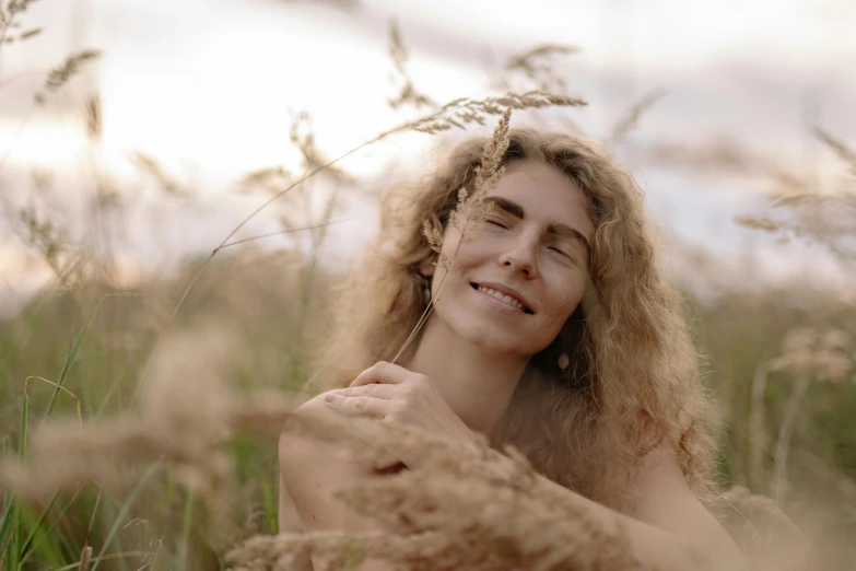 woman wearing ear rings and sitting in tall grass