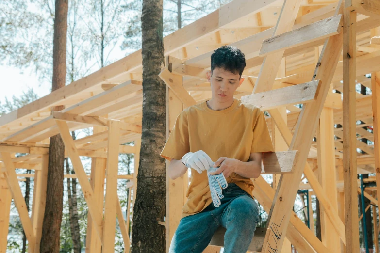 a young man holding two plastic bottles while kneeling on a ladder