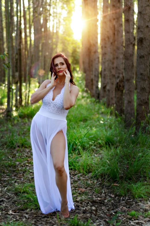 the girl in the long white dress walks in the woods