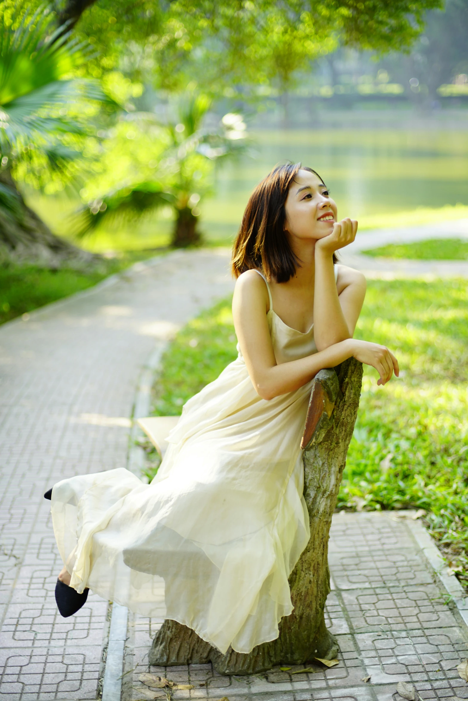 a young woman leaning on the trunk of a tree