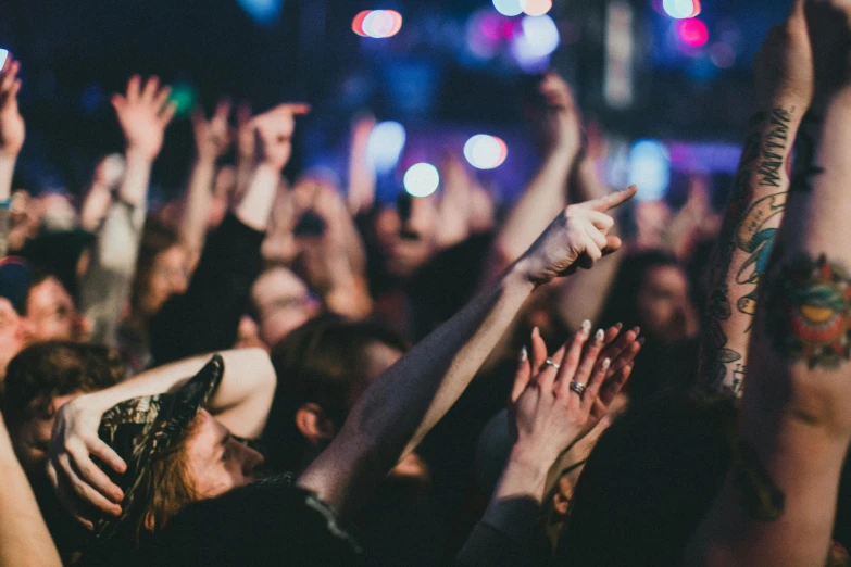 many people at a concert with their hands in the air