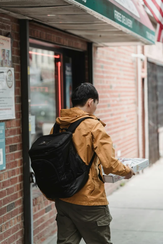 a man walking past a brick building with a backpack