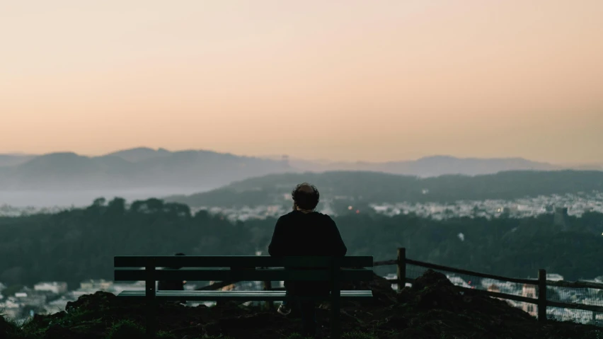 a person sits on a bench with the view of the hills
