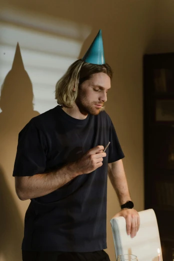 man with birthday hat looking at a cake