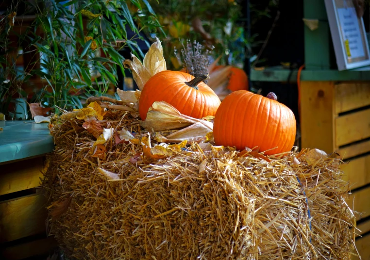 a pile of hay next to a container filled with plastic pumpkins