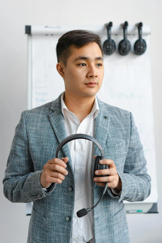 a man holding a steering wheel while standing next to a white board