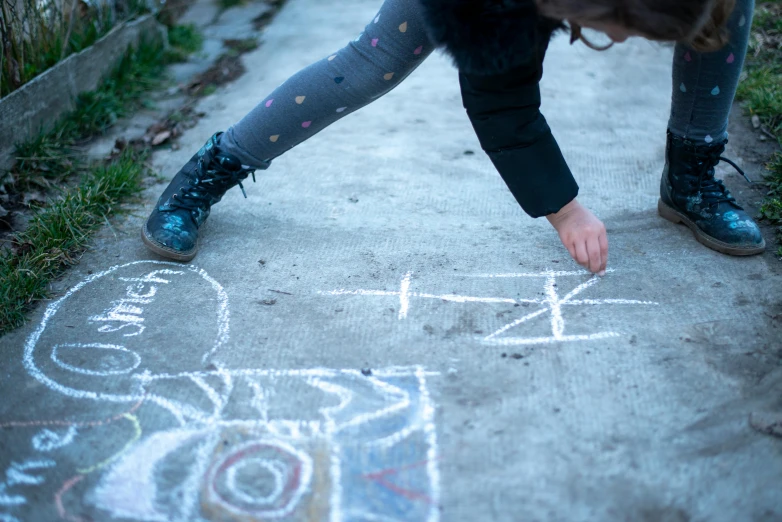 a person writing out soing in the sidewalk