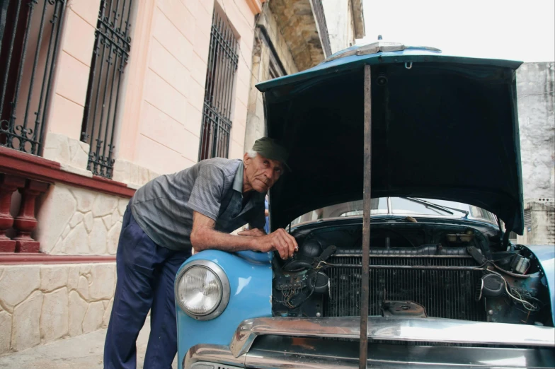 a man working on an old car in the street