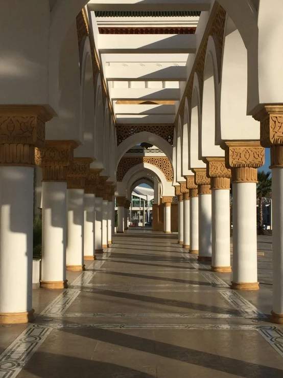 a long hallway with columns and arches leading into a shopping center