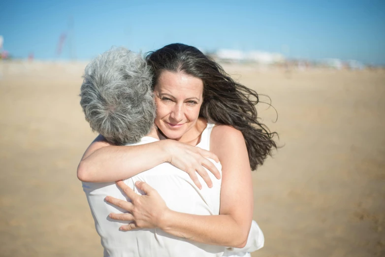 two women hugging and smiling while at the beach