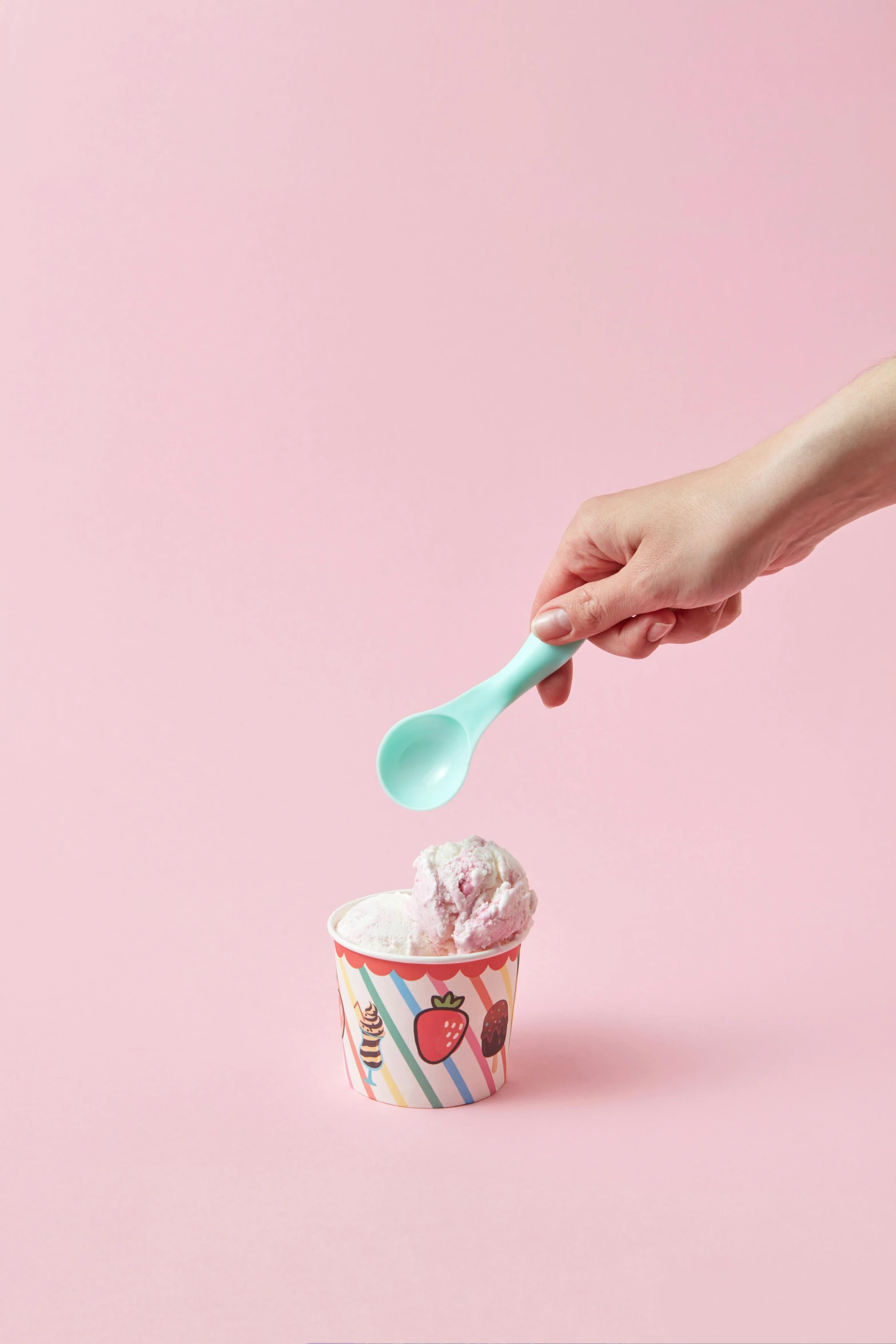 the woman's hand holds a spoon in a cup with ice cream