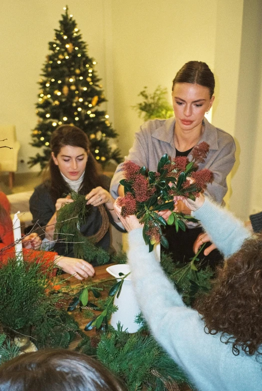 four women putting up the holiday greenery wreath