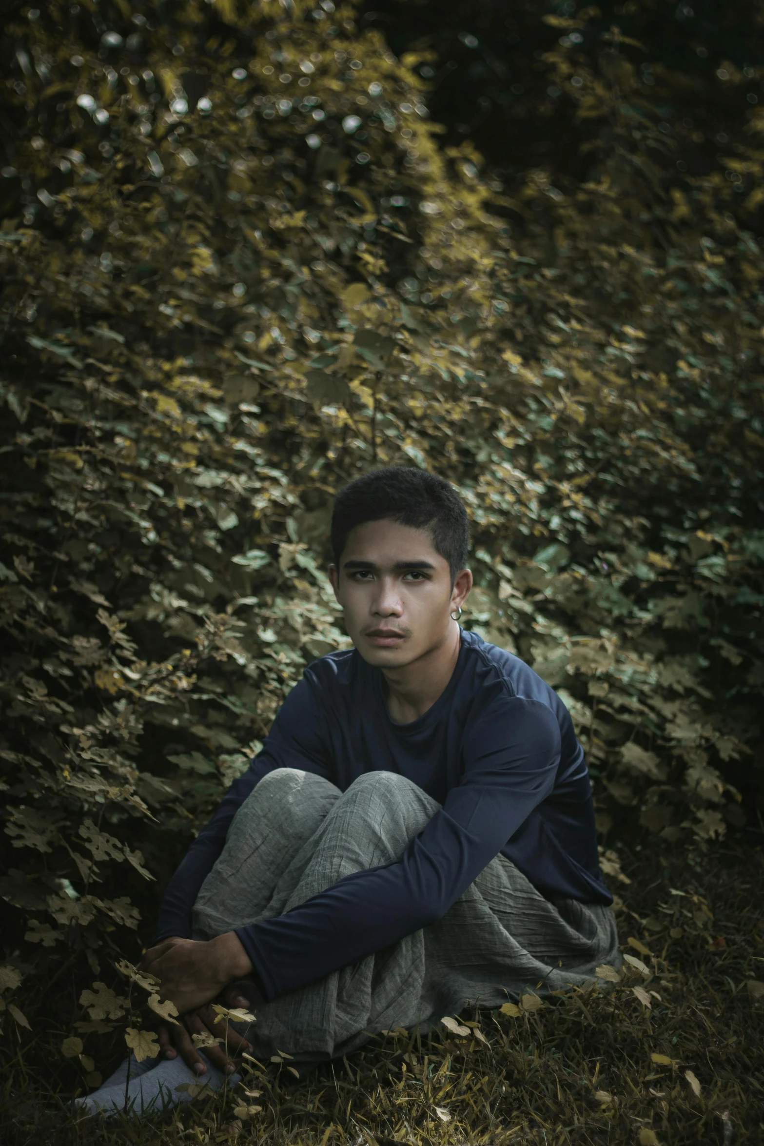 a young man sitting on the ground in a field