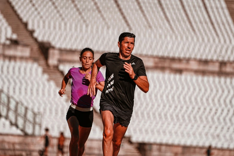 three people running on a track in the stadium