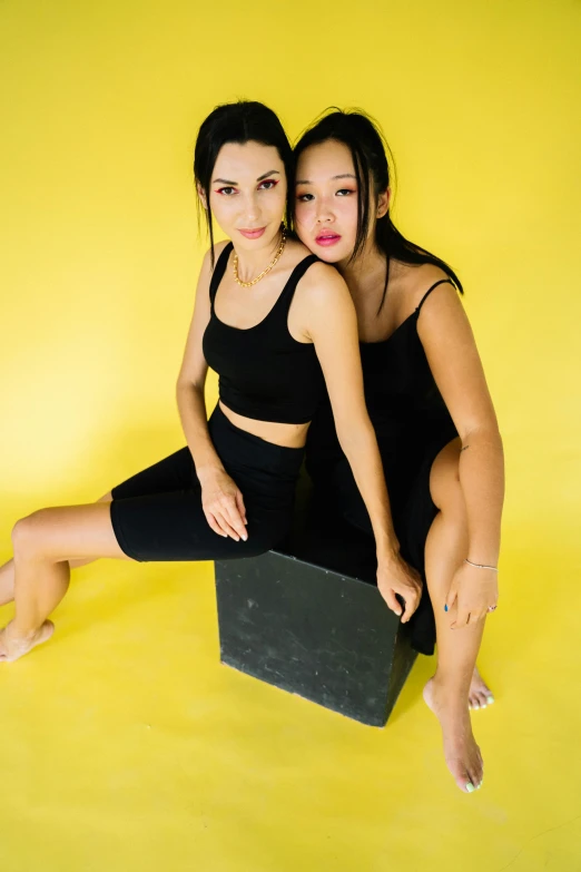 two girls are posing for a picture with a yellow background