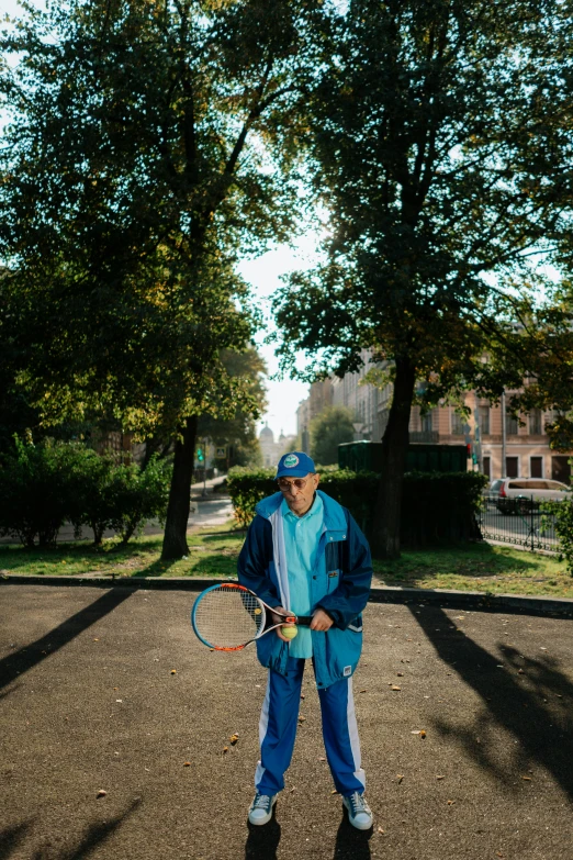 a man in blue pants and hat holding a racket