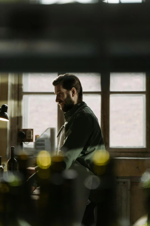 a man standing by a counter with a wine bottle