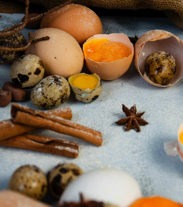 various eggs sitting on a countertop next to cinnamon sticks