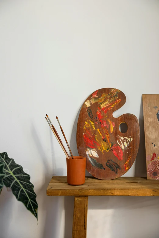 a couple of paintings on a shelf in front of a plant